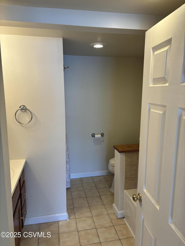 bathroom with tile patterned flooring, walk in shower, baseboards, toilet, and vanity