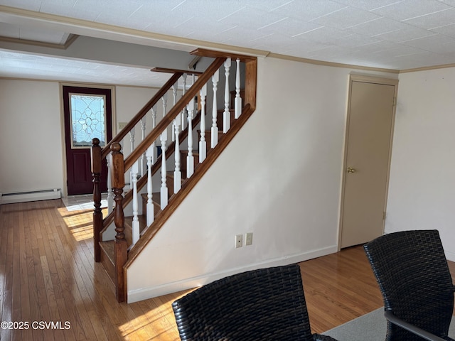 stairs featuring a baseboard radiator, baseboards, hardwood / wood-style floors, and ornamental molding