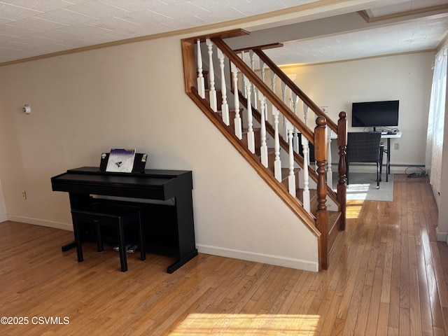 stairs featuring ornamental molding, baseboards, and wood-type flooring