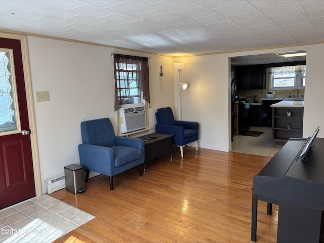 interior space featuring light wood-type flooring, a baseboard heating unit, cooling unit, and ornamental molding