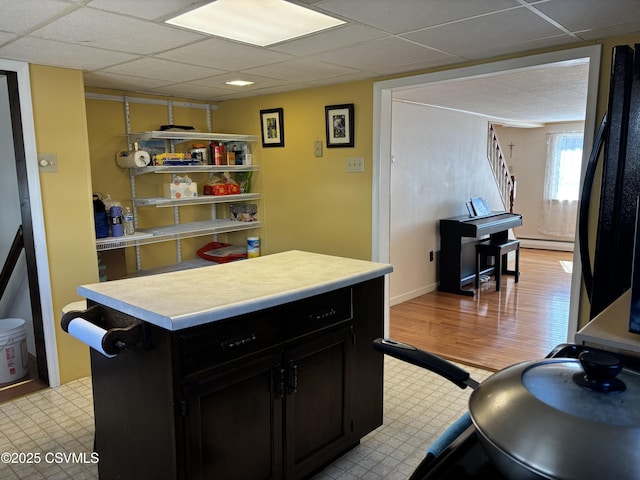 kitchen featuring dark cabinetry, a center island, light countertops, a baseboard radiator, and light floors