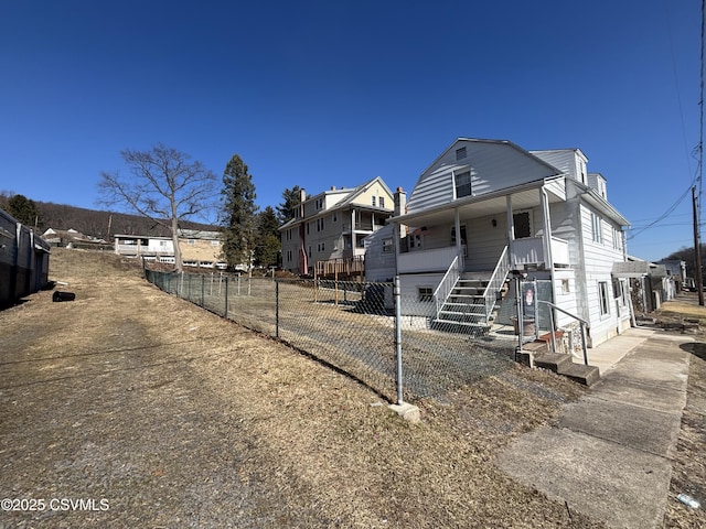 view of front of house featuring covered porch, stairs, and fence