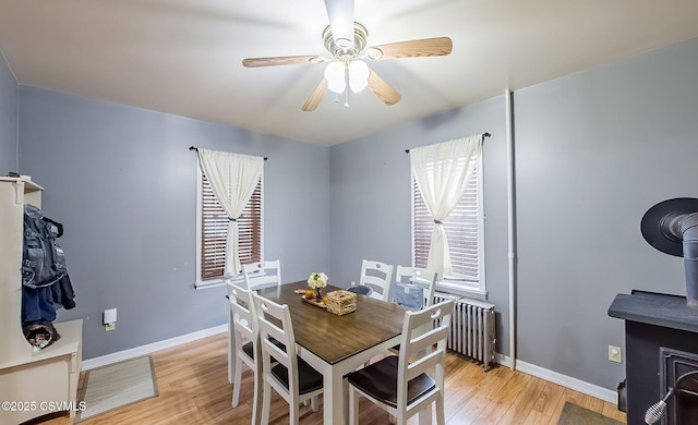 dining area with radiator, baseboards, light wood-type flooring, and ceiling fan