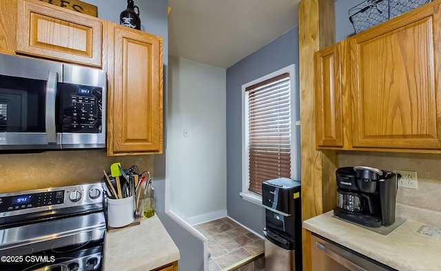 kitchen featuring stainless steel appliances, baseboards, stone finish floor, and light countertops