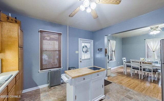 kitchen with baseboards, ceiling fan, butcher block countertops, radiator heating unit, and white cabinetry