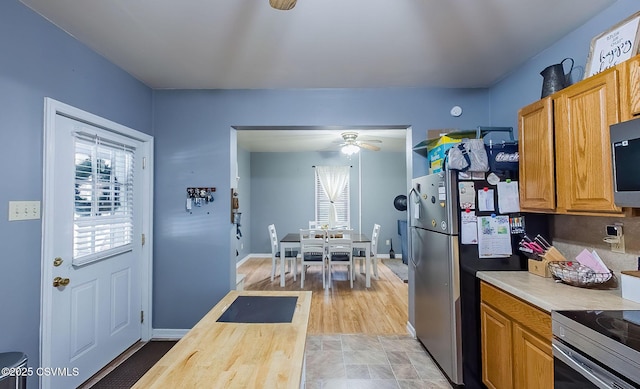 kitchen with ceiling fan, baseboards, appliances with stainless steel finishes, light wood-style floors, and brown cabinetry