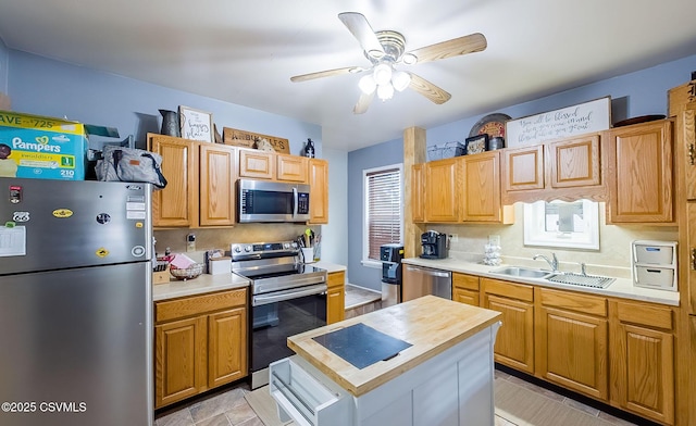 kitchen with a sink, a kitchen island, appliances with stainless steel finishes, and ceiling fan