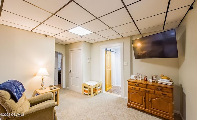 sitting room with a drop ceiling, baseboards, arched walkways, and carpet floors