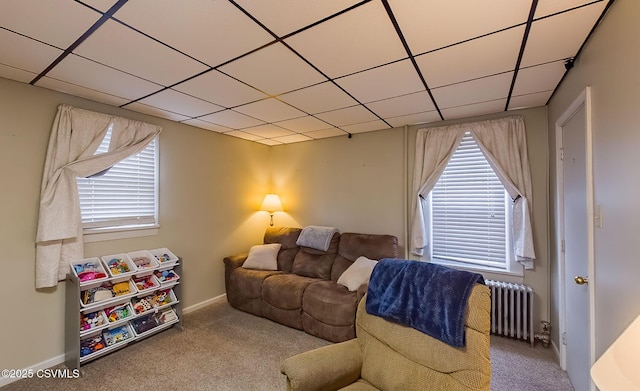 carpeted living room featuring baseboards, a paneled ceiling, and radiator heating unit