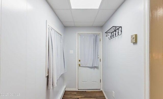 doorway to outside featuring a baseboard heating unit, a paneled ceiling, baseboards, and dark wood-style flooring