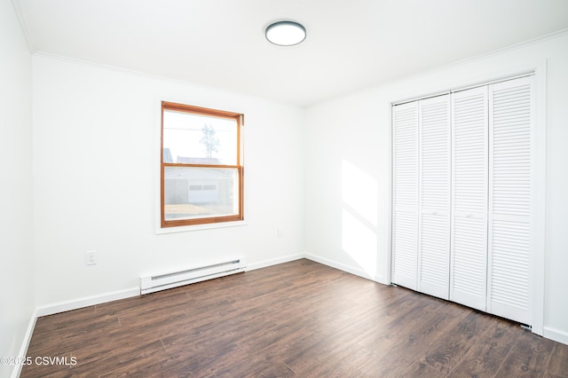 unfurnished bedroom with baseboards, ornamental molding, baseboard heating, a closet, and dark wood-style flooring