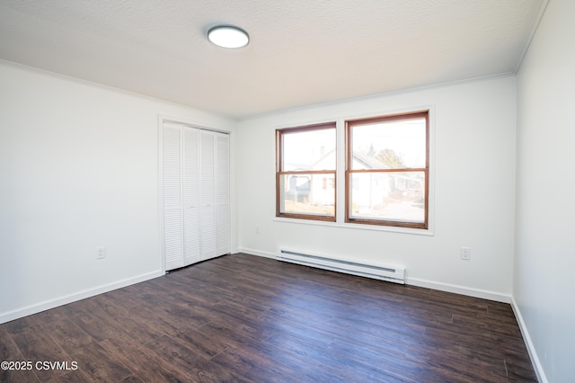 empty room featuring dark wood-type flooring, baseboards, baseboard heating, and a textured ceiling