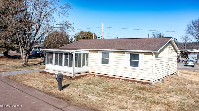 view of front of house with a front lawn, a sunroom, and a shingled roof