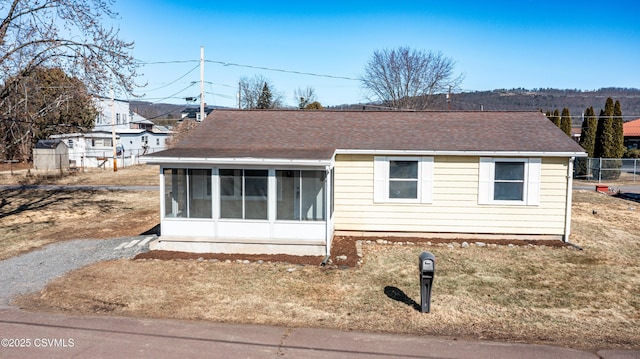 view of front of property featuring roof with shingles and a sunroom