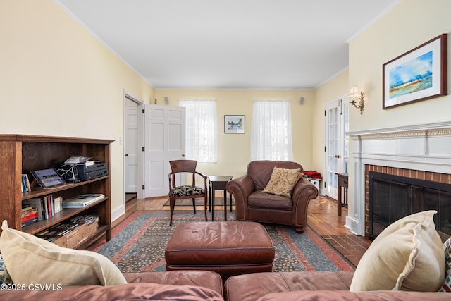 living area with a fireplace, crown molding, wood finished floors, and baseboards