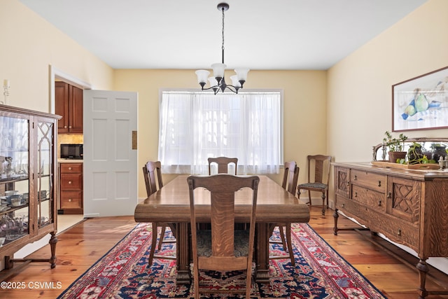 dining space with light wood finished floors and an inviting chandelier