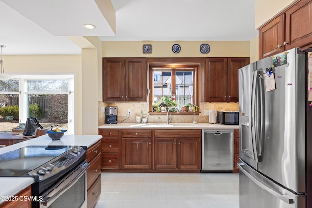 kitchen with light countertops, light floors, appliances with stainless steel finishes, and a sink