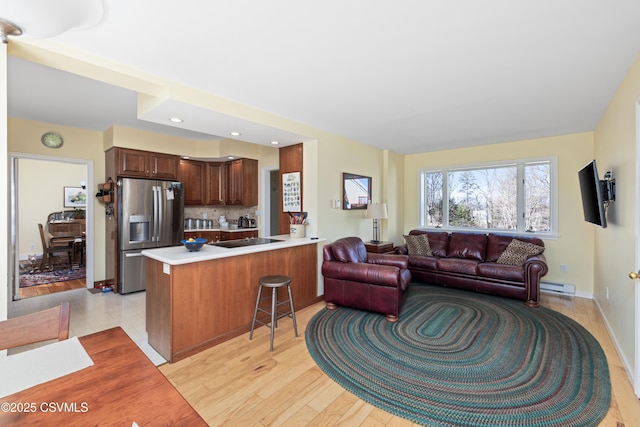 kitchen with black electric stovetop, open floor plan, light countertops, a peninsula, and stainless steel fridge