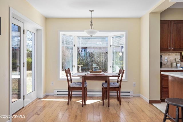 dining space featuring plenty of natural light, light wood-type flooring, and a baseboard radiator