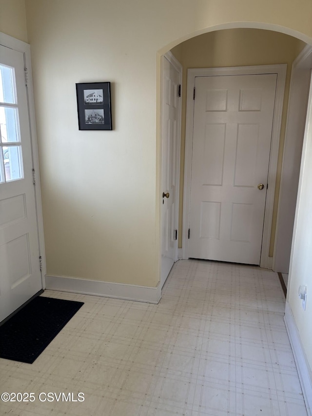 doorway featuring baseboards and light floors