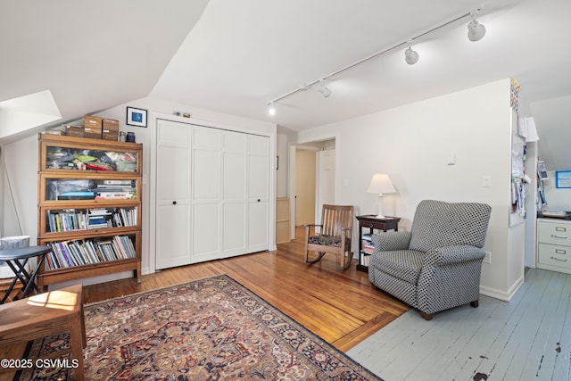 living area with hardwood / wood-style floors and track lighting