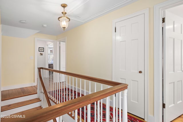 corridor with baseboards, an upstairs landing, and wood finished floors