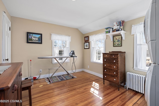 miscellaneous room featuring radiator, baseboards, light wood-style floors, and vaulted ceiling