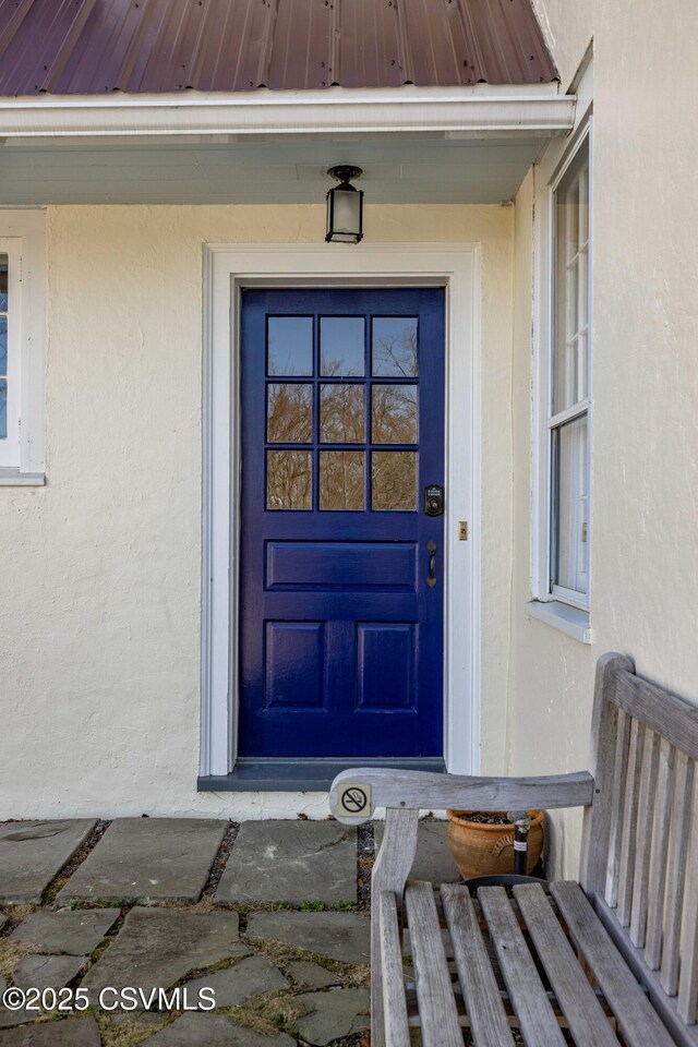 property entrance featuring a standing seam roof, metal roof, and stucco siding