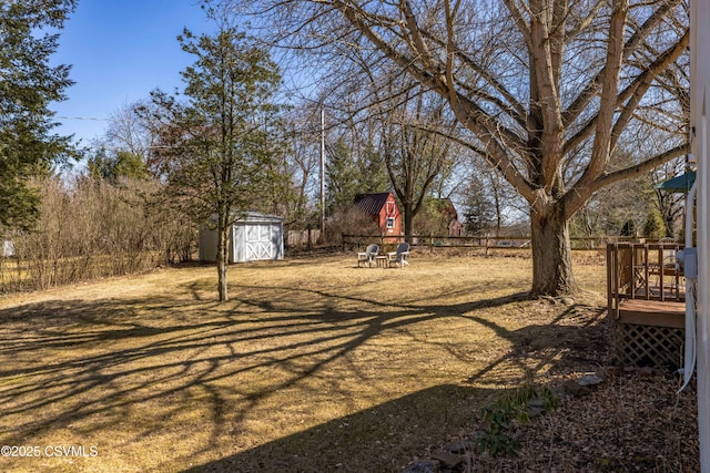 view of yard featuring a deck, a storage shed, an outbuilding, and fence