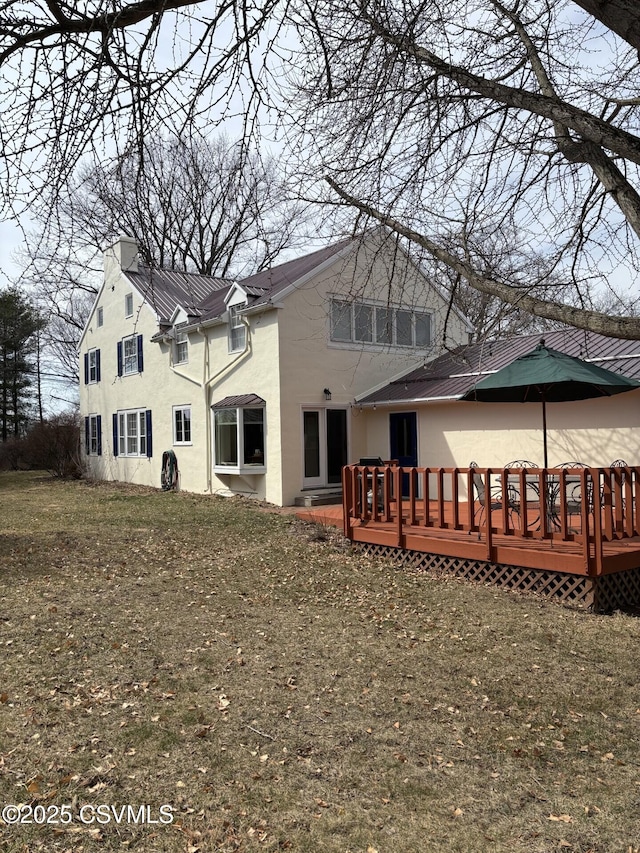 rear view of property featuring stucco siding, metal roof, and a wooden deck