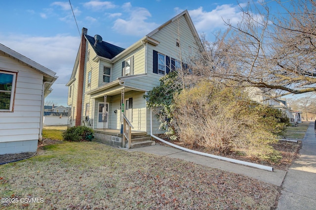 view of front of home featuring a front yard, a porch, and a chimney