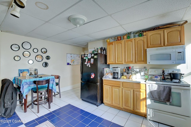 kitchen featuring a drop ceiling, white appliances, light countertops, light tile patterned floors, and baseboards