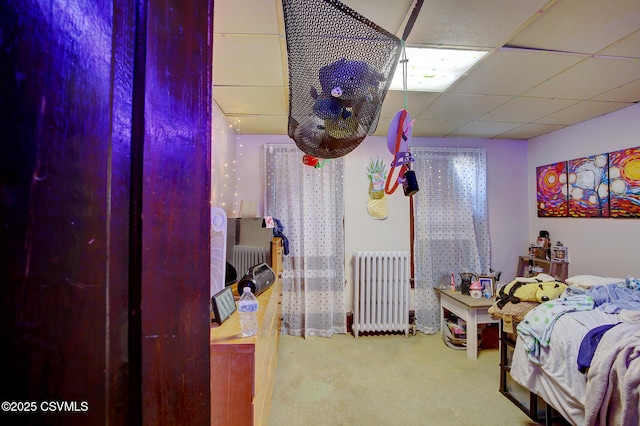 bedroom with carpet flooring, radiator, and a drop ceiling