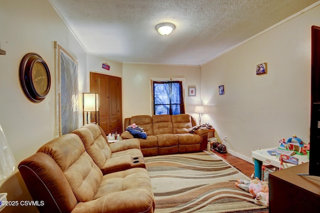 living area with ornamental molding, a textured ceiling, baseboards, and wood finished floors