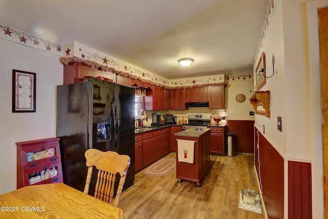 kitchen with ventilation hood, a wainscoted wall, light wood finished floors, electric stove, and black fridge with ice dispenser