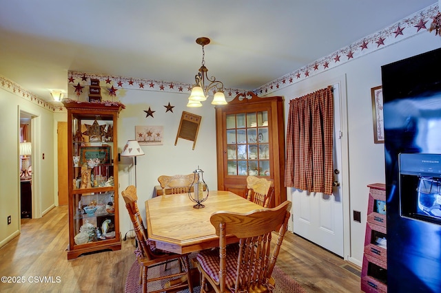 dining space featuring light wood-type flooring and a chandelier