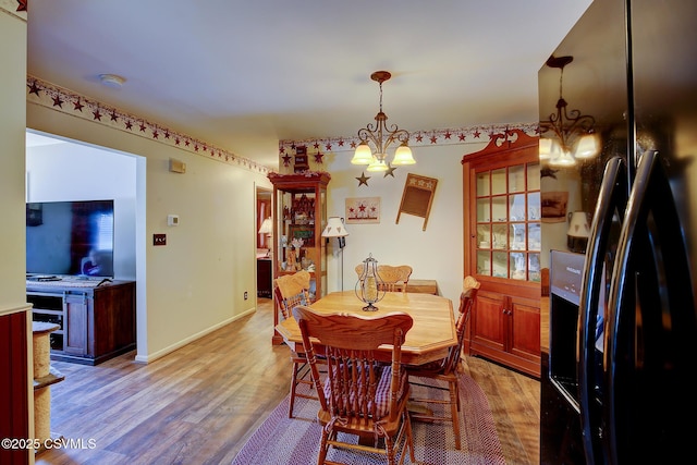 dining room featuring a notable chandelier, baseboards, and light wood-type flooring