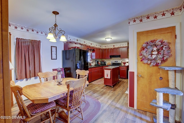 dining area with light wood-style flooring and an inviting chandelier