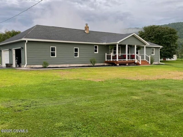 back of property featuring roof with shingles, a porch, a chimney, a garage, and a lawn