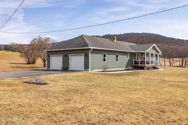 view of front of home featuring driveway, roof with shingles, an attached garage, covered porch, and a front lawn