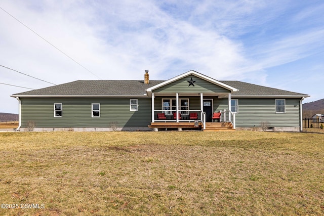 back of property with a yard, covered porch, and a shingled roof