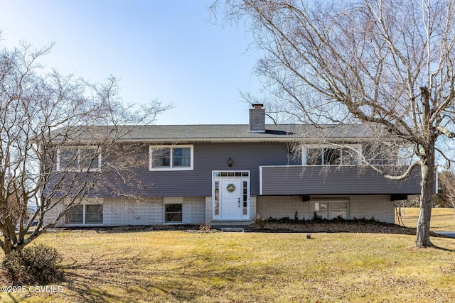 raised ranch featuring brick siding, a chimney, a front yard, and entry steps