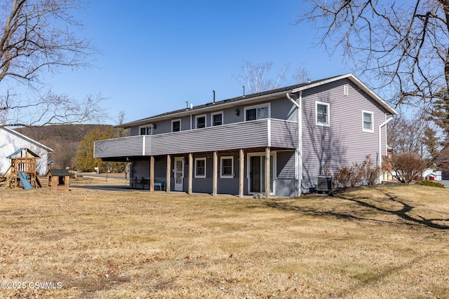 rear view of house featuring a lawn, a playground, and central AC