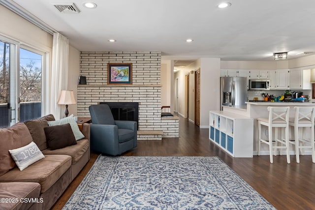 living room featuring dark wood finished floors, recessed lighting, visible vents, and a fireplace