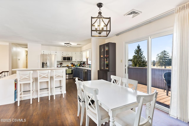 dining area with an inviting chandelier, visible vents, and dark wood-style flooring