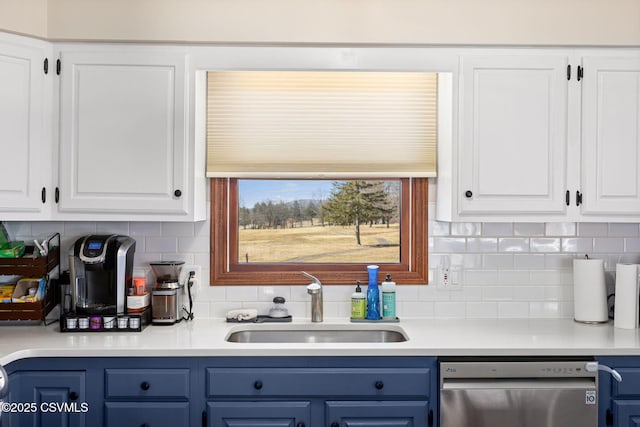 kitchen with blue cabinetry, light countertops, stainless steel dishwasher, white cabinets, and a sink