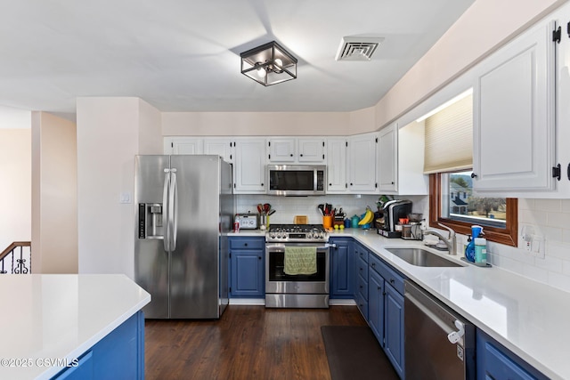 kitchen featuring blue cabinetry, appliances with stainless steel finishes, light countertops, and a sink