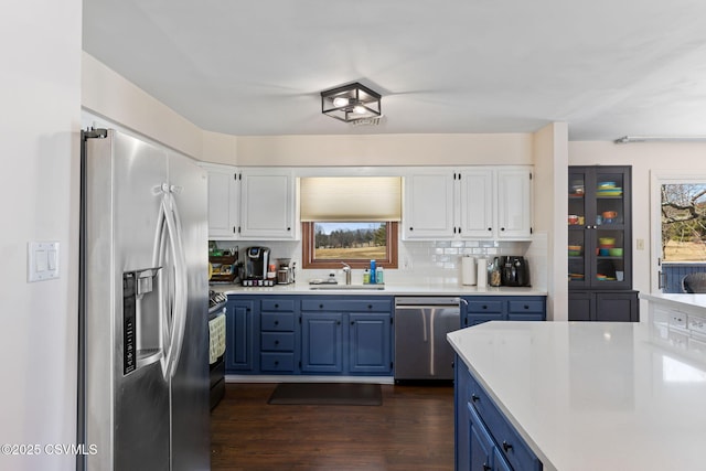 kitchen with blue cabinetry, a sink, white cabinetry, stainless steel appliances, and light countertops