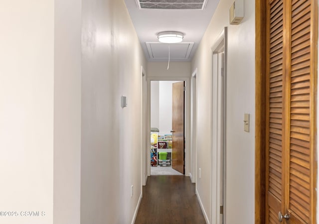 hallway with visible vents, a heating unit, baseboards, dark wood finished floors, and attic access