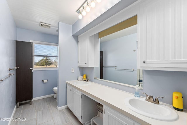 bathroom featuring double vanity, toilet, visible vents, and a sink